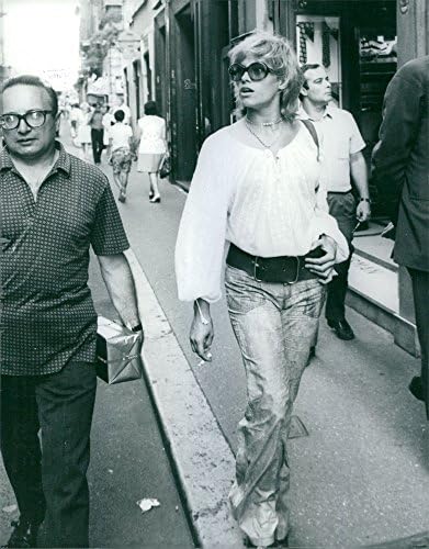 Foto vintage de Nathalie Delon andando na calçada.